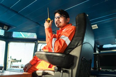 Filipinli güverte subayı gemi ya da gemi köprüsünde. GMDSS VHF radyosunda konuşuyor.