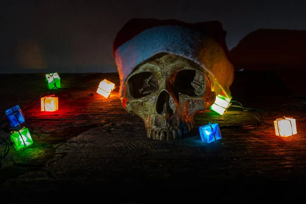 Stillleben Totenkopf tragen Weihnachtsmann Hut mit Geschenk Blinker Licht. — Stockfoto