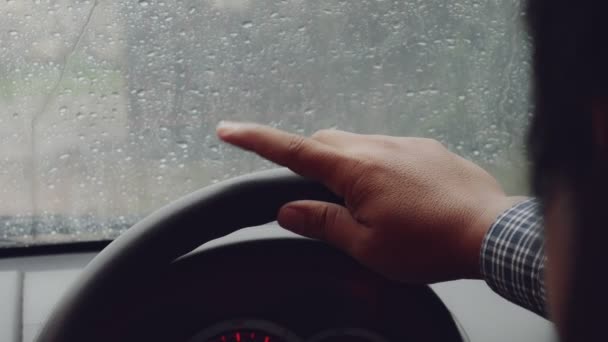 Man händerna på ratten på bilen fokus i. Fingrarna knacka på hårt regn. — Stockvideo