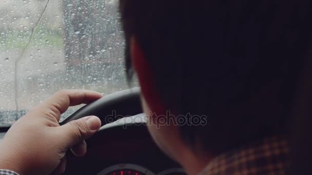 Muž ruce na volant auto zaměření. Prsty klepat na hustý déšť. — Stock video