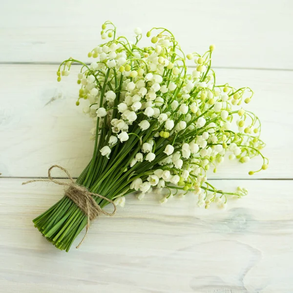 A bouquet of lilies of the valley on a wooden surface.
