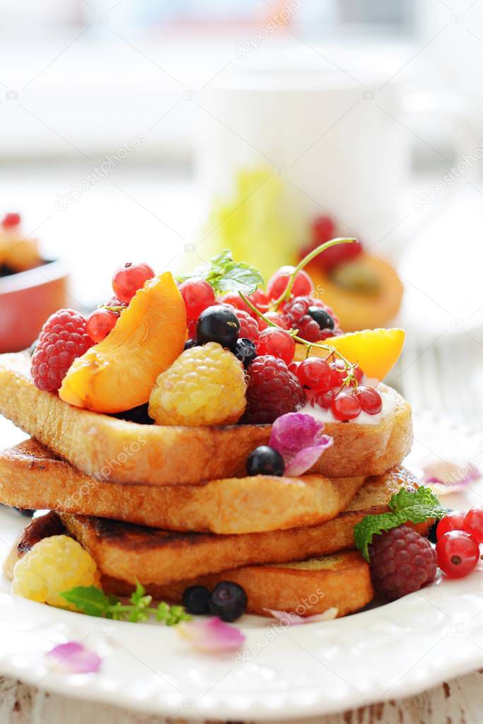 A delicious summer breakfast with French toasts and fresh berries and fruits. Appetizing picture in light colors. French Toast