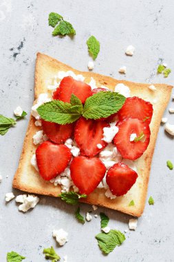 Kahvaltıda çilekli tost, nane ve süzme peynir. Sağlıklı kahvaltı, kızarmış ekmek. Geleneksel Amerikan ve Avrupa yaz kahvaltısı: tost böğürtlenli sandviç.