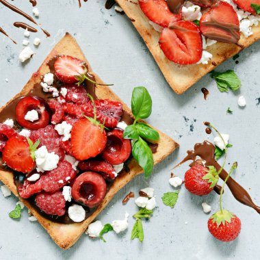 Kahvaltıda çilekli tost, ahududu, kiraz, nane ve süzme peynir. Sağlıklı kahvaltı, kızarmış ekmek. Geleneksel Amerikan ve Avrupa yaz kahvaltısı: tost sandviçleri 