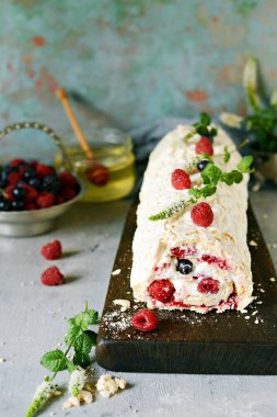 Meringue roll with a gentle airy cream, mint and fruit filling from raspberries, black currants, blueberries. Pavlova summer sweet dessert