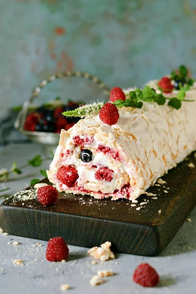 Meringue roll with a gentle airy cream, mint and fruit filling from raspberries, black currants, blueberries. Pavlova summer sweet dessert