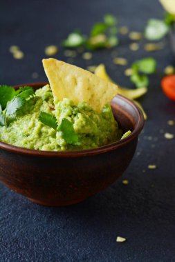 Bir kase mısır cipsli guacamole sosu ve mavi arka planda seçici odaklı malzemeler. Meksika ulusal yemeği.