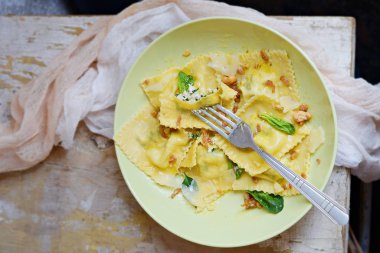 Italian food. Home made fresh Ravioli pasta with spinach and ricotta cheese, fresh basil and, black pepper, parmesan cheese and Butter Sauce on a light aged background.