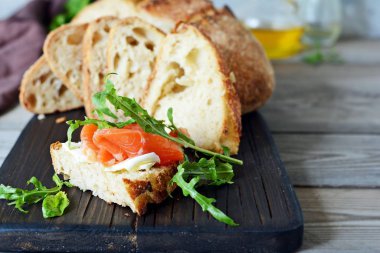 Biraz tuzlanmış somon, roka, tohum ve süzme peynirli sandviç. Ekmekli tost, tuzlu balık, smorrebrod.