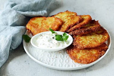 Yeşil salata ve yoğurt soslu çıtır patates krep. Patates böreği yığını