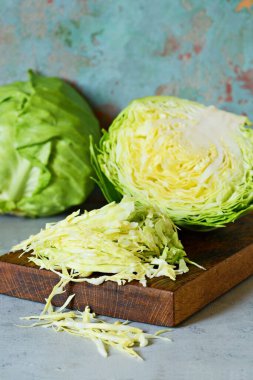 Ahşap mutfak tahtasındaki taze lahana mavi arka planda öğütülmek için. Salata kesmek için sebze. Vejetaryen yemeği, diyet, vitamin.