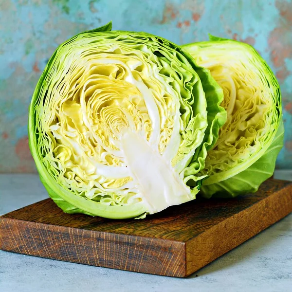 Ahşap mutfak tahtasındaki taze lahana mavi arka planda öğütülmek için. Salata kesmek için sebze. Vejetaryen yemeği, diyet, vitamin.