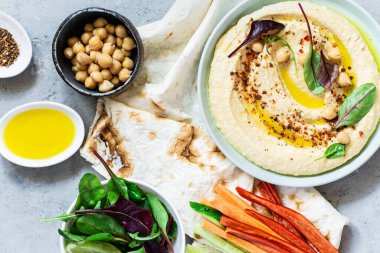 Şifalı otlar, kırmızı biber, zeytinyağı, pide, sebze çubuğu ve marul içeren klasik humus. Sağlıklı vegan yiyecekler. Bir tabak Orta Doğu mutfağı. Sağlıklı beslenme konsepti.