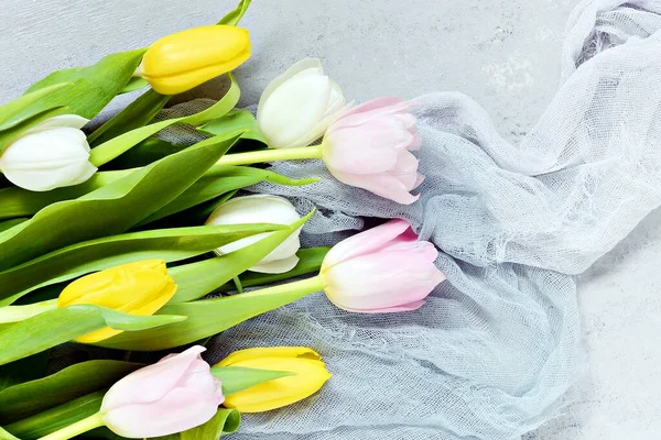 Spring color tulips in a bouquet  on a gentle blue background. Flowers as a gift, a romantic spring mood. Women\'s day, mother\'s day greeting concept. Copy space, close up, top view, flat lay.