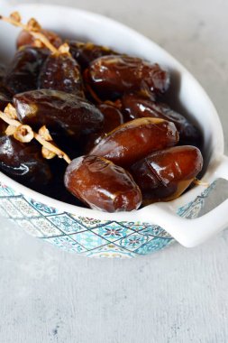 Gri-mavi arkaplanda sulu tarihli bir kase. Sağlıklı ve lezzetli yemekler. Çiğ Organik Medjool Tarihleri 