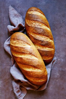 Kahverengi arka planda taze ekmek. Geleneksel buğday taze rustik ekmek, bir somun ekmek.