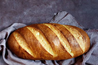 Kahverengi arka planda taze ekmek. Geleneksel buğday taze rustik ekmek, bir somun ekmek.