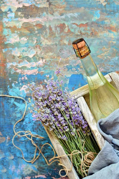 Wooden box with a bottle of chilled champagne and a bouquet of lavender. Romantic present, gift.