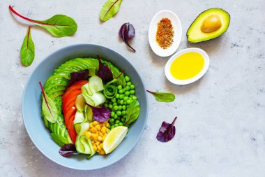 Sağlıklı vejetaryen yemekleri. Taze sebze, salatalık, domates, mısır, yeşil bezelye, avokado, mavi arka planda bir kasede marul. Sağlıklı yeme kavramı.