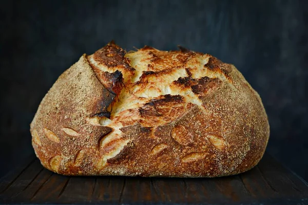 Homemade Freshly Baked Country Bread  made from wheat and whole grain flour on a dark background. French Freshly baked bread. Slicing homemade bread