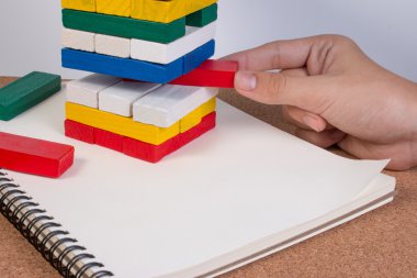 Vintage closeup el çocuğun yığın oyuncak ahşap blok üzerinde bir blok almak. Risk kavramları.
