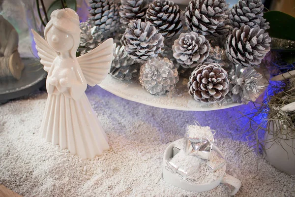 White ceramic fairy or angel on white snow decorate with pine cone.