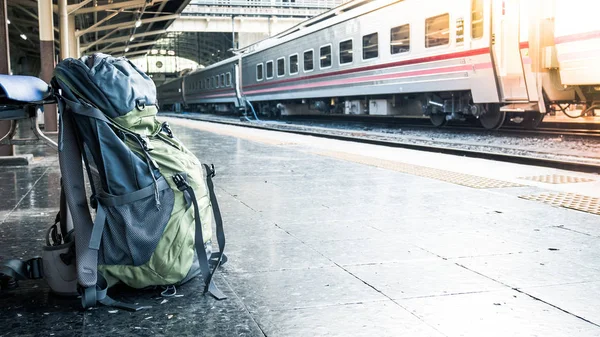 Mochila en el suelo de la estación de tren para esperar. Bolsa de viaje en la estación de tren con filtro vintage . — Foto de Stock