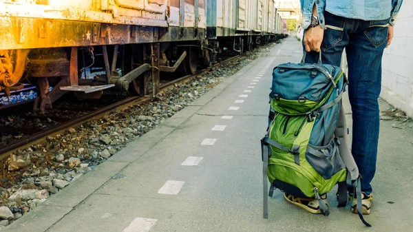 Mochilero esperando un viaje largo en la estación de tren con mochila. Concepto de viaje con filtro vintage . — Foto de Stock