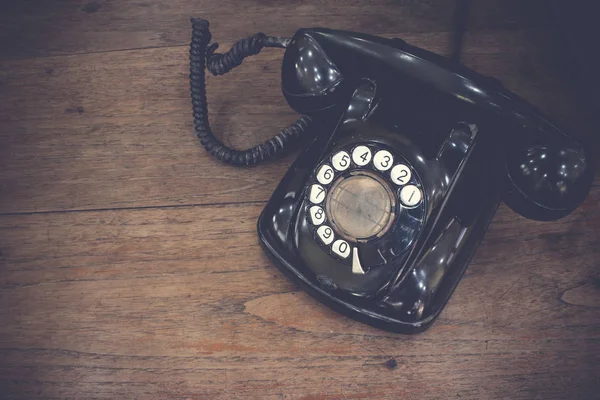 Fekete antik vintage analóg telefon tárcsázás vagy görgetés telefon fa asztalon. Lépjen kapcsolatba velünk. — Stock Fotó