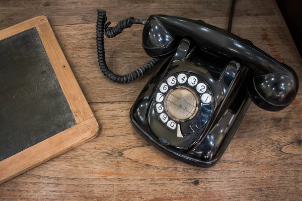 Fekete antik vintage analóg telefon tárcsázás vagy tekerő telefon régi falon a régi pala. Lépjen kapcsolatba velünk koncepció. — Stock Fotó