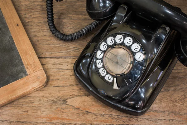 Fekete antik vintage analóg telefon tárcsázás vagy tekerő telefon régi falon a régi pala. Lépjen kapcsolatba velünk koncepció. — Stock Fotó