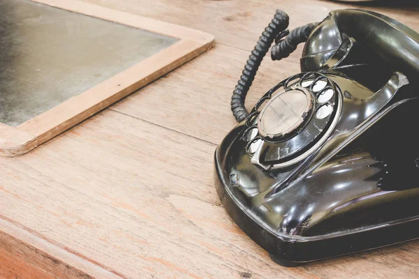 Fekete antik vintage analóg telefon tárcsázás vagy tekerő telefon régi falon a régi pala. Lépjen kapcsolatba velünk koncepció. — Stock Fotó