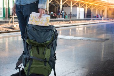 Uzun bir yolculuk seyahat sırt çantası ile tren istasyonunda bekleyen backpacker. Seyahat konsepti vintage filtreli etkilenir.