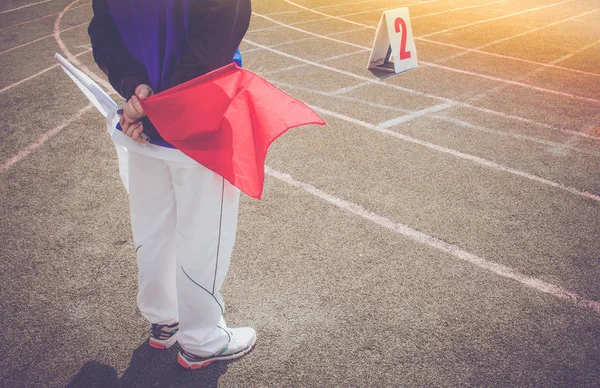 陸上競技場で白と赤の旗を掲げて走るアシスタントレフリー又はラインマン — ストック写真