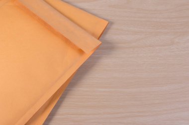 Sarı boş zarfın şeffaf kabarcık şal veya ambalaj ahşap masaya darbeye dayanıklı ile kullanılan.