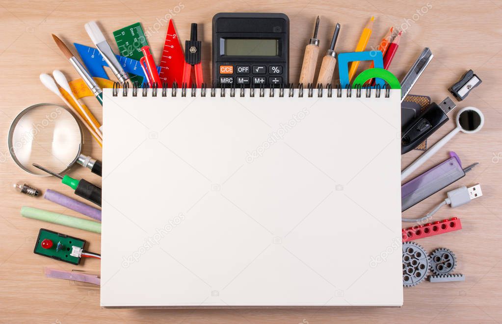 Notebook over school supplies or office supplies on school table. Background with school or office material with copy space for text.