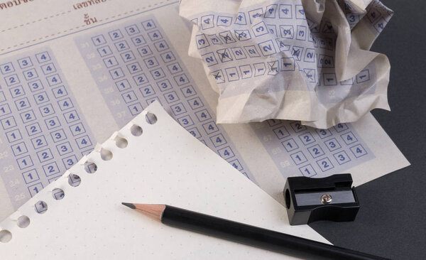 Crumpled paper ball of vintage classic answer sheet with pencil, sharpener and paper reduction. Cross the right answer in the box with blank answer. Answer sheet concept.