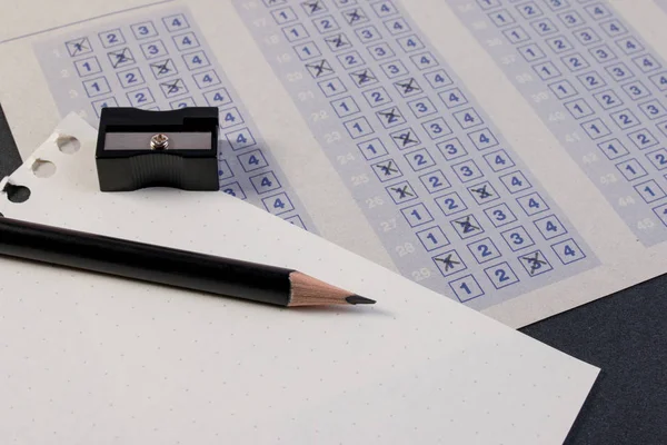 Filling out in answer sheet with pencil, sharpener and paper reduction. Cross the right answer in the box with blank answer. Vintage classic multiple choice answer sheet on table. — Stock Photo, Image