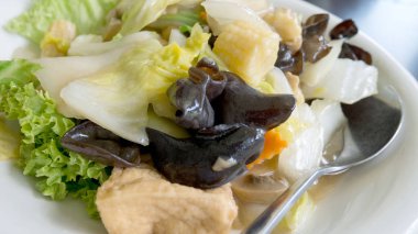 Beyaz plaka üzerinde siyah tablo arka plan üzerinde tavada kızartılmış karışık sebze. Vejetaryen veya sağlıklı gıda kavramı. En sevdiğim Çin ana yemek tarifleri.