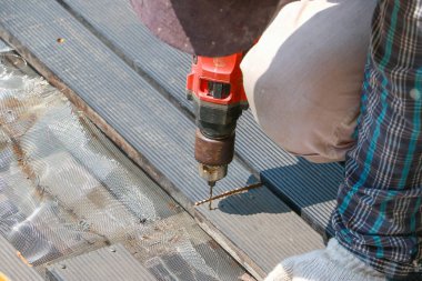 Marangoz el ya da el alt iş dükkanında elektrik drell makinasıyla ahşap tahta ile bir delik matkap.