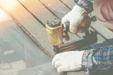 Marangoz el veya işçinin el hava nailer makine çalışma mağazasında kullanarak ahşap tahta ile bir delik matkap.