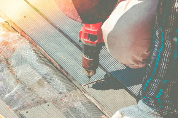 Carpenter ruku nebo ruce pracovníka vrtá otvor s dřevěnou prkennou pomocí elektrické drell stroje v dílně. — Stock fotografie