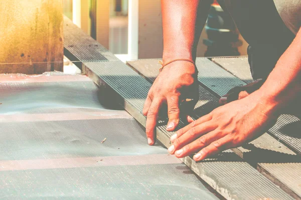 Carpenter hand or hand of worker flooring wood on the floor in work shop. Vintage effect style.