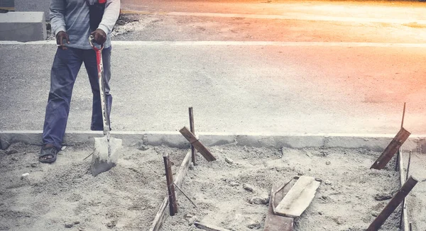Neidentifikovaný pracovník pracuje kope díru s shvel a rýč v písku na silnici staveniště. Koncepce výstavby silnice. — Stock fotografie