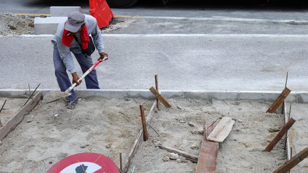 Oidentifierade arbetstagaren arbetar gräver ett hål med en shvel och spade i sanden på vägen byggarbetsplats. Road construction koncept. — Stockfoto