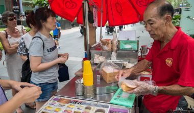 SINGAPORE - MAR 21, 2017 : Unidentified man sells ice cream sandwich wafer in front of main shopping mall the popular place for shopping at Orchard Road, Singapore. clipart