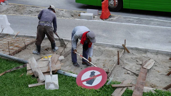 Kuala Lumpur, Malajsie - 22 březen 2017: Neznámý dělník pracující kope díru s lopatou a rýč v písku na silnici staveniště. v Kualum Lumpure, Malajsie. — Stock fotografie