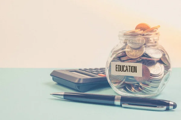 Money saving for education fee or school free in the glass bottle with book and pen on blue background in pastel color effect.