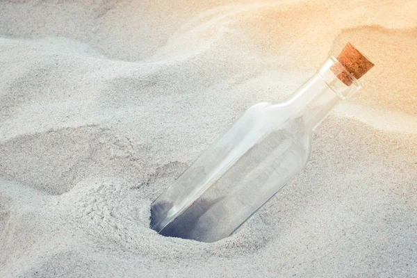Old vintage empty glass bottle with natural tapered cork lid on the sand beach close-up. — Stock Photo, Image