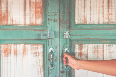 Eski ahşap slayt kapı açık metal kapı kolu tutan Asya el.